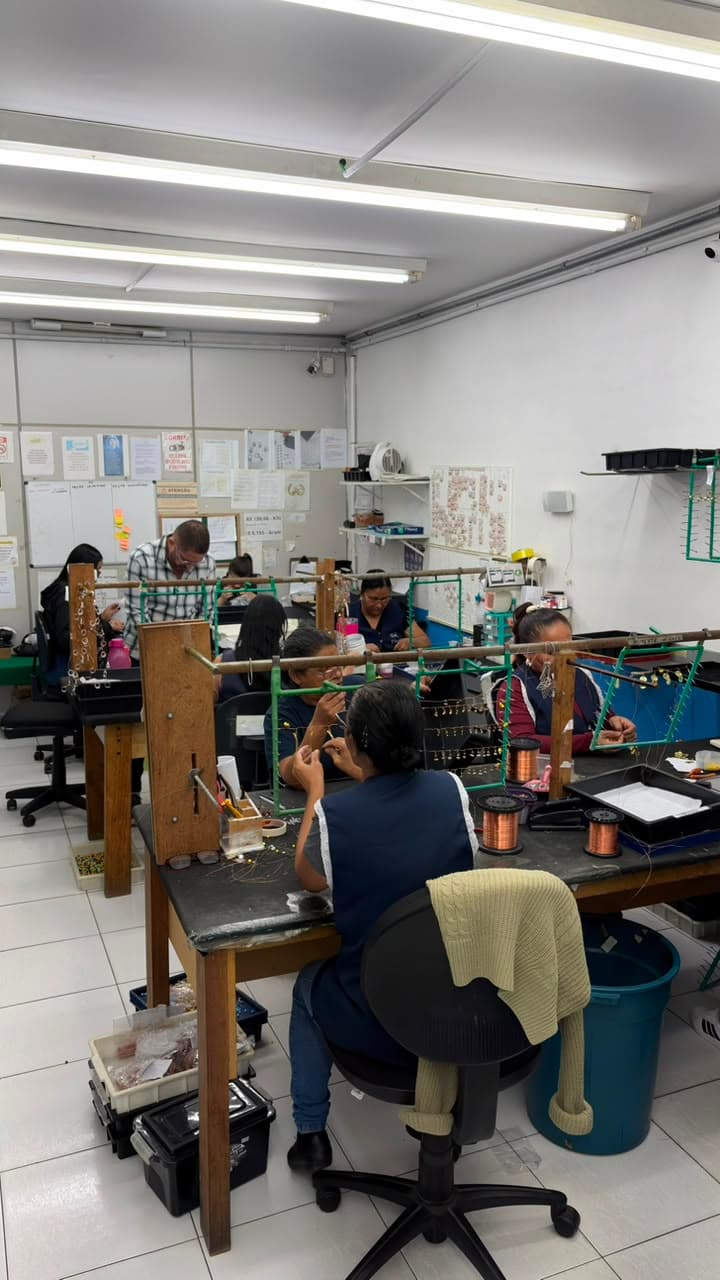Equipe montando peças em gancheiras no setor de acabamento